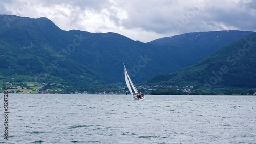 Sailboat sailing in slo motion in blue sea water.