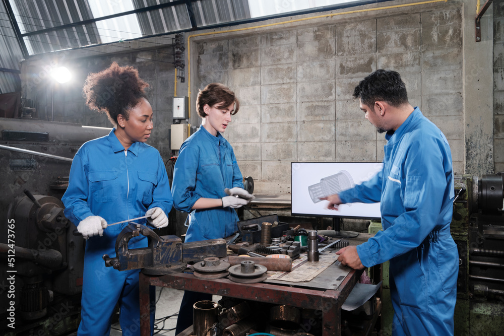 Three multiracial professional industry engineer workers teams in safety uniforms metalwork jobs discuss with mechanical drawing in a monitor, lathe machines, and workshop in manufacturing factory. Three multiracial professional industry engineer workers teams in safety uniforms metalwork jobs discuss with mechanical drawing in a monitor, lathe machines, and workshop in manufacturing factory.