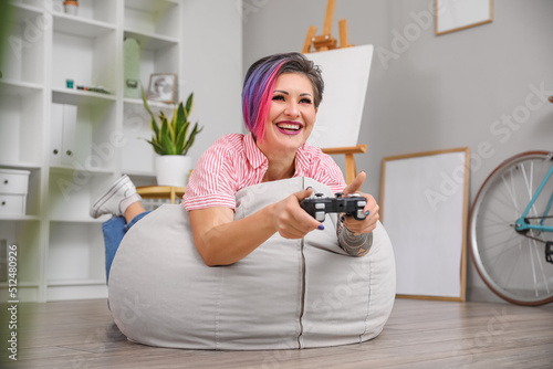 Beautiful woman with dyed hair playing video game at home