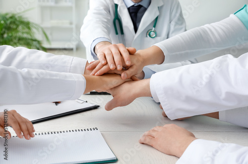 Group of doctors putting hands together in clinic