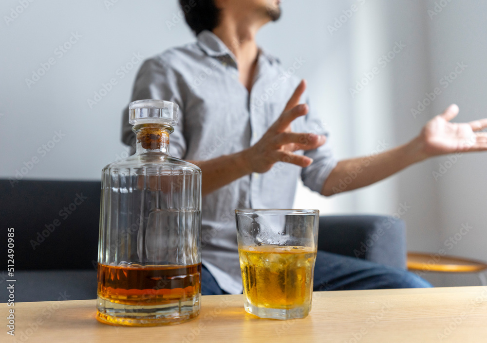 Man enjoy a glass of whiskey sitting at sofa at home.
