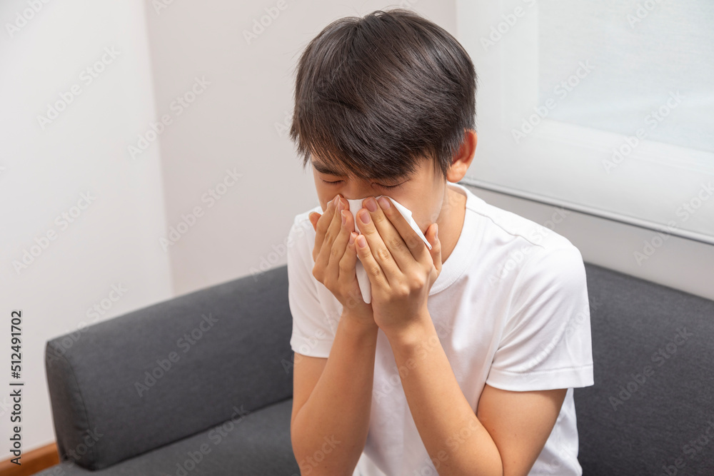Sick Asian preteen boy blowing nose and sneeze at home, healthcare concept. Sick Asian preteen boy blowing nose and sneeze at home, healthcare concept.