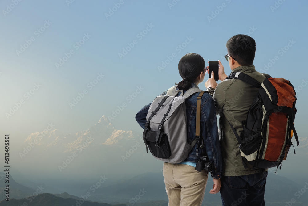 Young traveler man and girl with the backpack on the top of iceberg mountain in the nature and using smartphone searching direction on location map, Adventure and travel concept