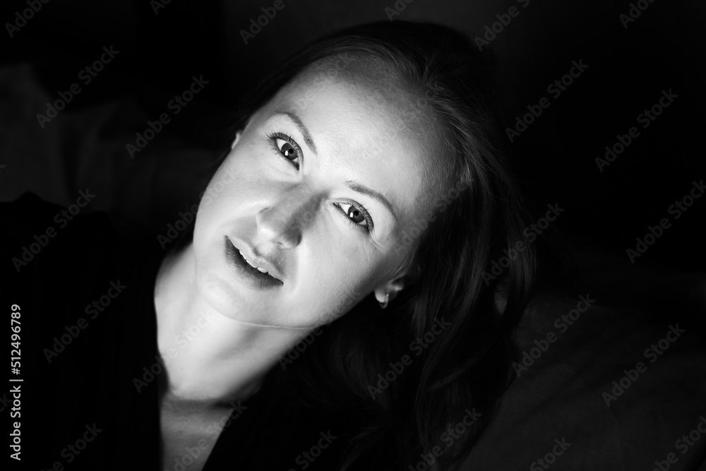 Black and white photo of an attractive woman. A large portrait on a dark background. Front view.