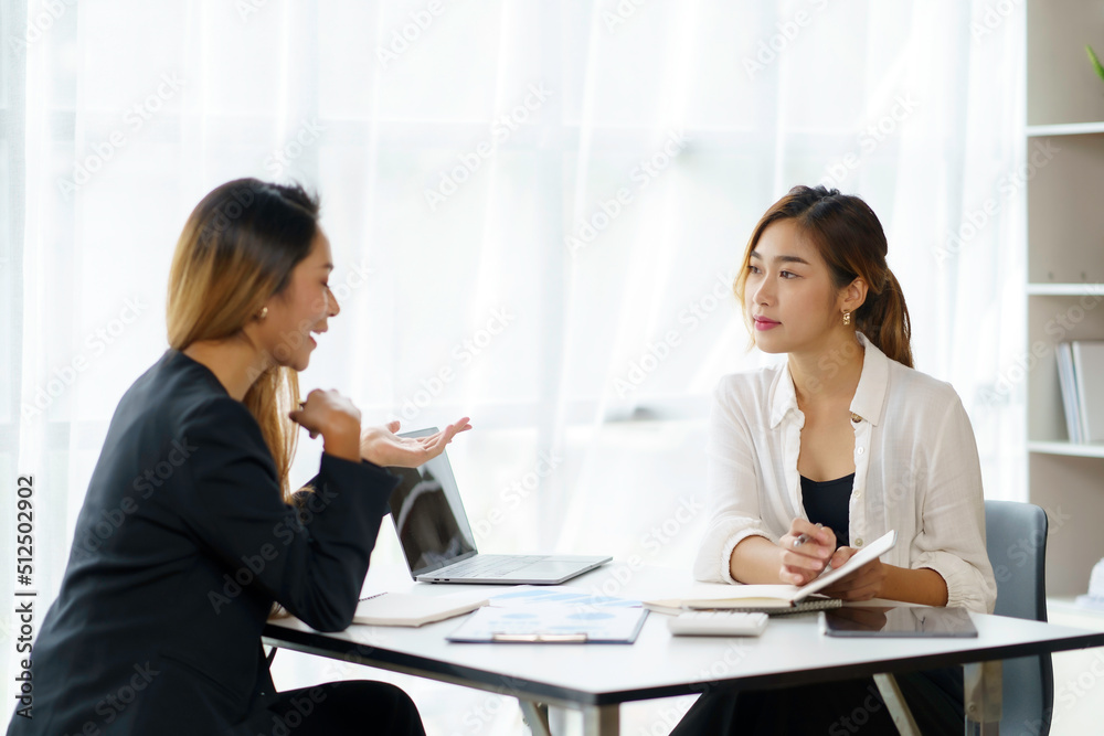 Two young Asian professional businesswomen working talking in a modern startup. Two young Asian professional businesswomen working talking in a modern startup.