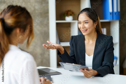 Two young Asian professional businesswomen working talking in a modern startup.