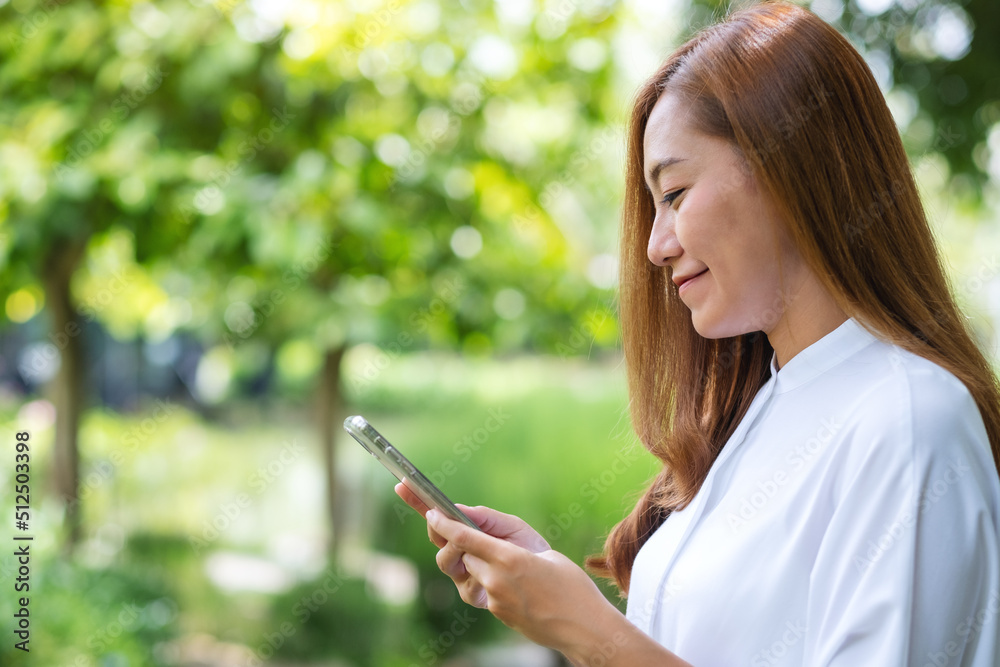 Portrait image of a beautiful young woman holding and using mobile phone in the outdoors Portrait image of a beautiful young woman holding and using mobile phone in the outdoors