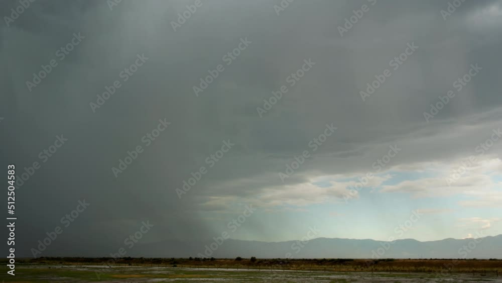 Time lapse of rainstorm moving overhead in flat landscape viewing blue sky through the water curtains.