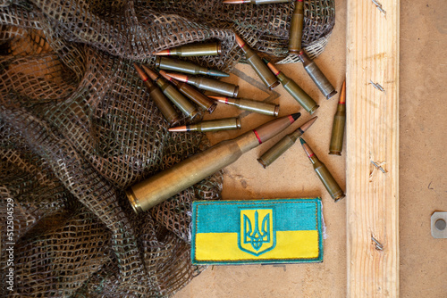 Pili lie on a green cloth on a board and next to it lies a stripe with the flag of Ukraine, the war in Ukraine, ammunition