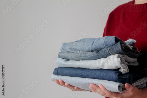 woman holding pile of jeans on white background © jajam_e