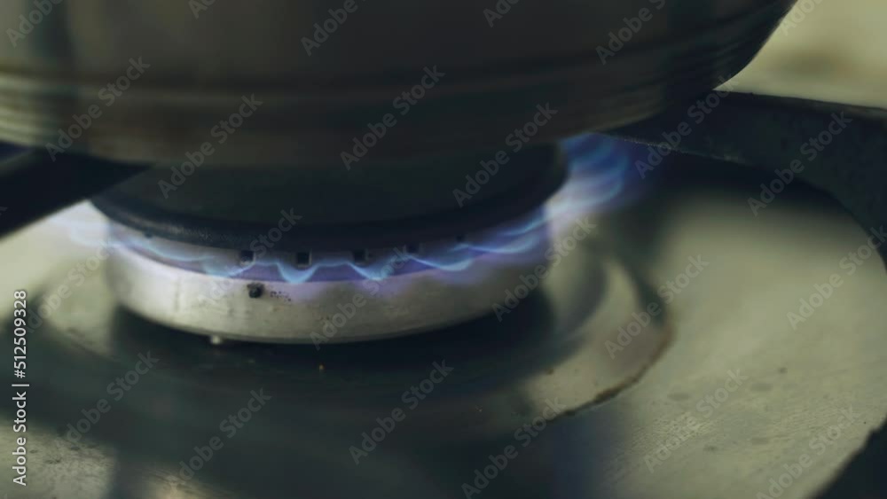 Close-up of a burning gas stove burner. There is a pot on the gas. Close-up of a burning gas stove burner. There is a pot on the gas.