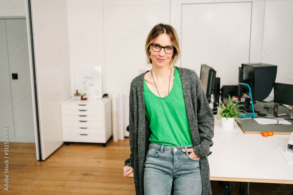 businesswoman sitting on desk in office and looking to the camera