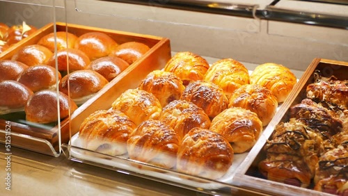 Assorted pastry and bread arranged on tray selling at bakery shop.