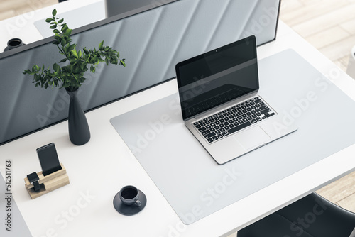 Close up and top view of creative white designer workplace with blank mock up laptop computer screen with reflections, partition, coffee cup, decorative plant and supplies. 3D Rendering.