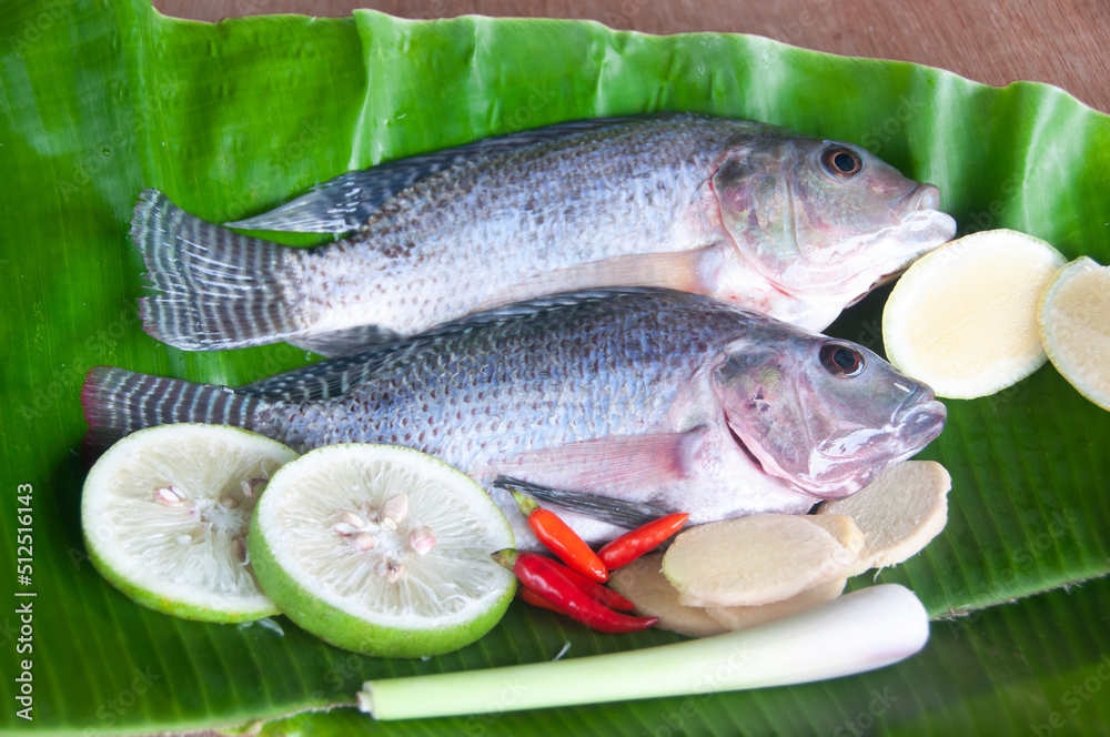 Fresh tilapia fish with lemongrass, lemon and chili on banana leaf. Fresh tilapia fish with lemongrass, lemon and chili on banana leaf.