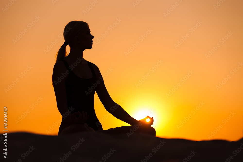 silhouette of a person in yoga pose in a sunset