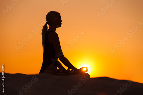 silhouette of a woman meditating in a sunset