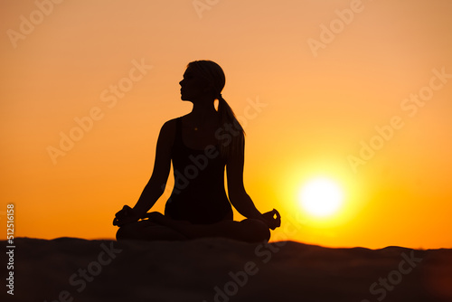 silhouette of a woman meditating in a sunset