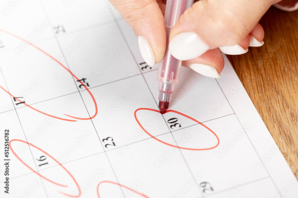 close up on employee woman hand using red pen to writing schedule on 30 day calendar 2022 to make an appointment meeting or manage timetable each day at house for work from home concept close up on employee woman hand using red pen to writing schedule on 30 day calendar 2022 to make an appointment meeting or manage timetable each day at house for work from home concept
