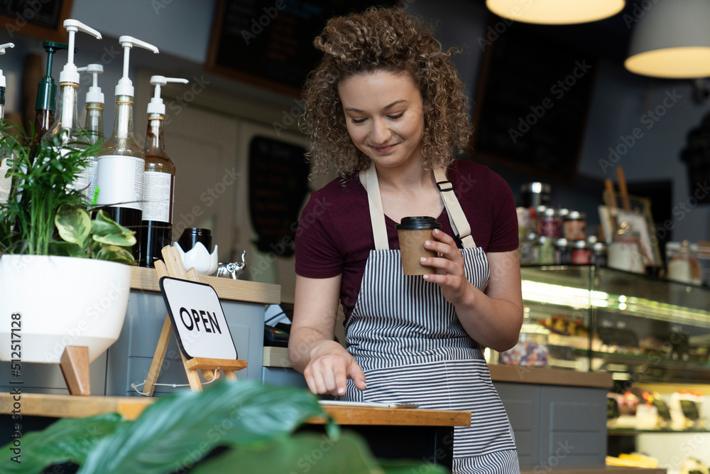 Young caucasian waitress using phone in the kitchen Young caucasian waitress using phone in the kitchen