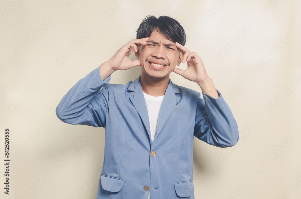 young asian man wearing college suit having headache on isolated background young asian man wearing college suit having headache on isolated background