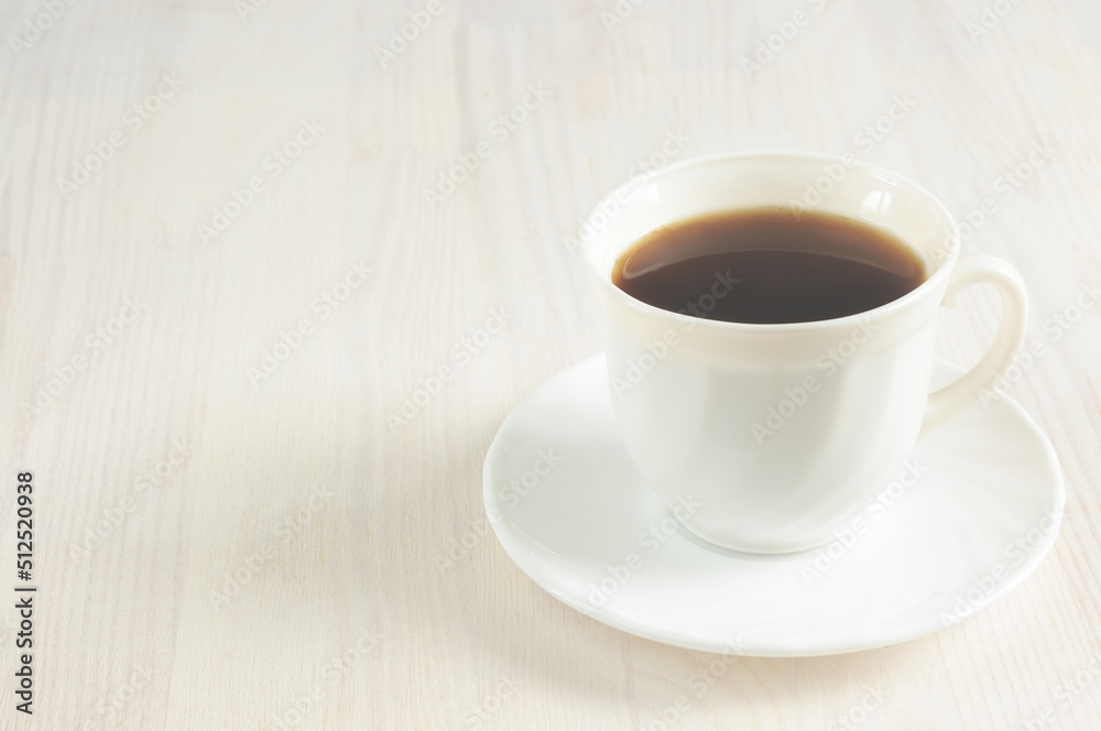 A cup of invigorating black coffee on a light wooden background. Selective focus, toned image, natural light. copy space for text A cup of invigorating black coffee on a light wooden background. Selective focus, toned image, natural light. copy space for text