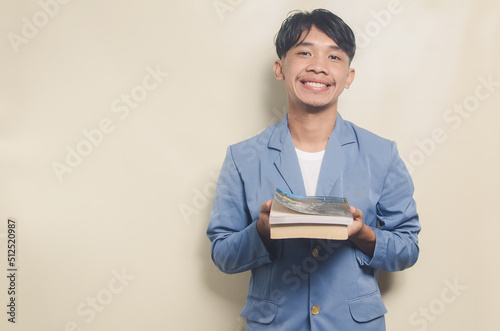 young asian man wearing college suit with expression showing book on isolated background