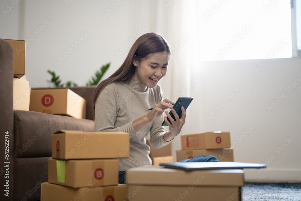 Happy asian female, small stock business owner holding phone and retail package parcel boxes checking commercial shipping delivery order on smartphone using mobile app technology. Happy asian female, small stock business owner holding phone and retail package parcel boxes checking commercial shipping delivery order on smartphone using mobile app technology.