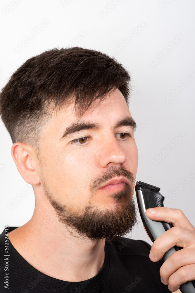 european man shaves his beard with a trimmer european man shaves his beard with a trimmer