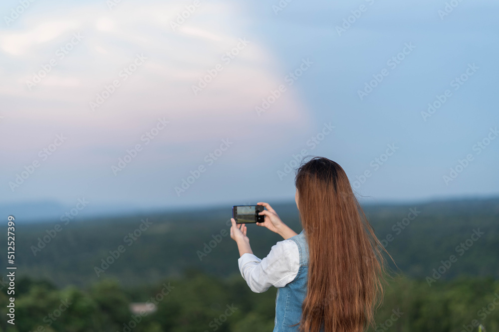 Back view portrait of a woman taking photo of a landscape with a smart phone Back view portrait of a woman taking photo of a landscape with a smart phone