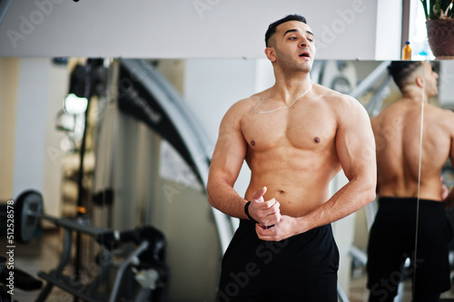 Muscular arab man training in modern gym. Fitness arabian men with naked torso doing exercises .