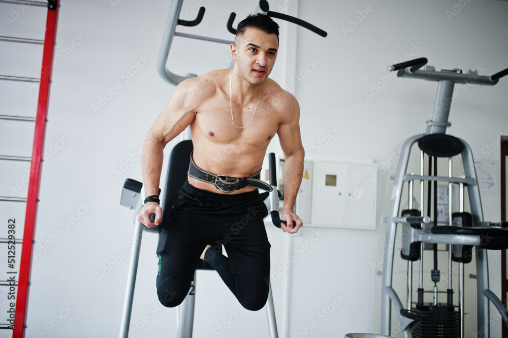 Fototapeta premium Muscular arab man training in modern gym. Fitness arabian men with naked torso doing exercises .