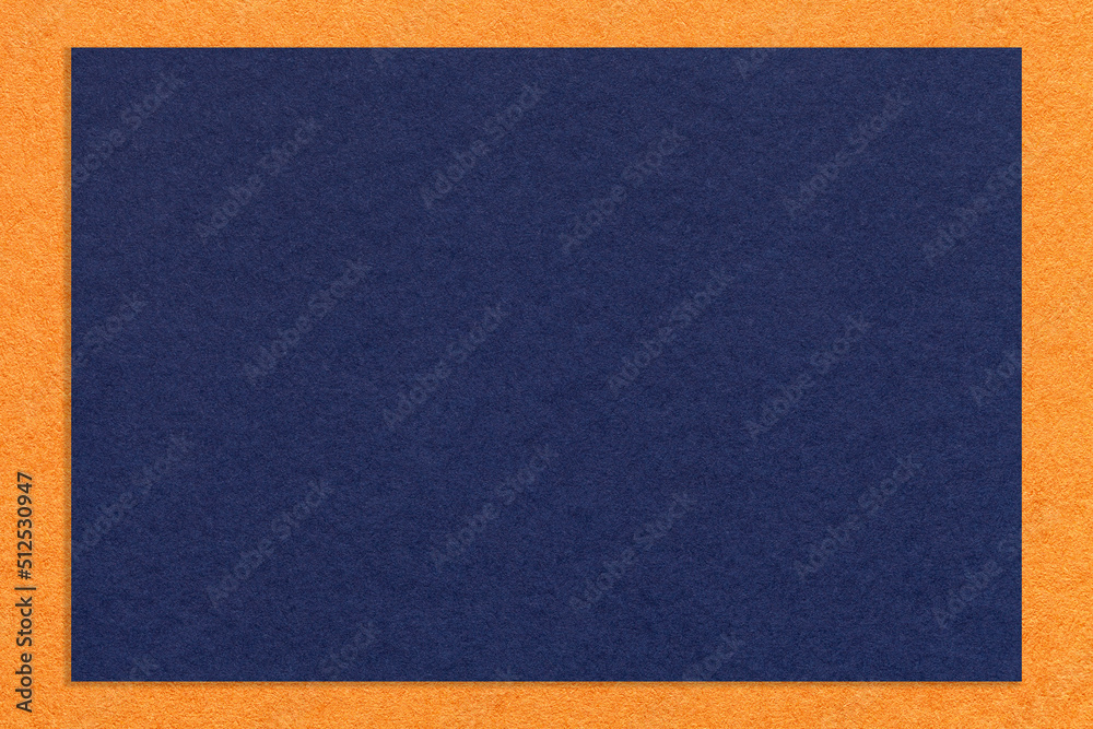 Fototapeta premium Texture of craft navy blue color paper background with orange border, macro. Structure of ultramarine cardboard