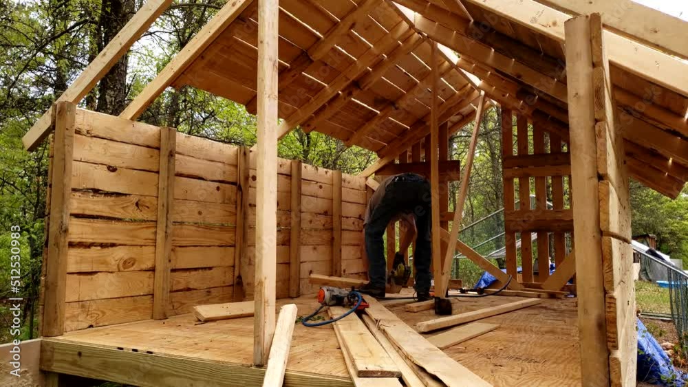 Inside of chicken house while being under construction next to wooded area.