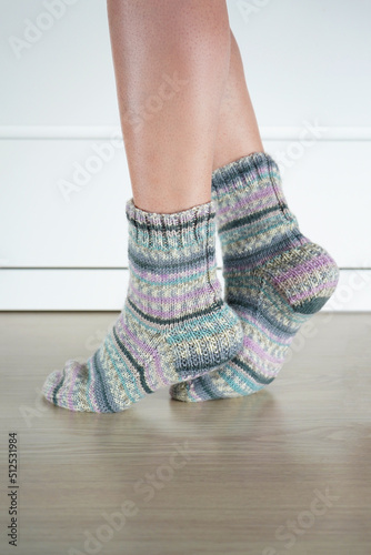 Legs of a girl in knitted striped socks on the floor