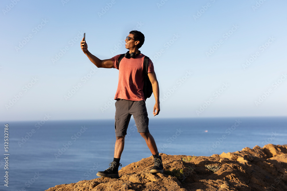 Young man taking selfie photo on a road trip. Man making memories on the mountain..