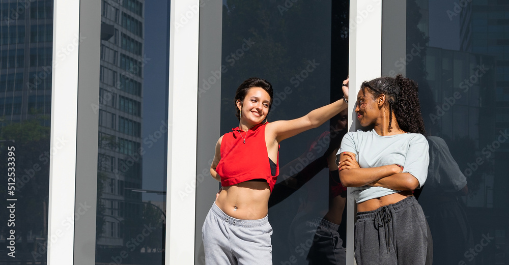Confident diverse women near wall Confident diverse women near wall