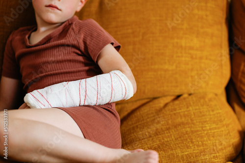 Anonymous cute boy with broken arm on couch photo