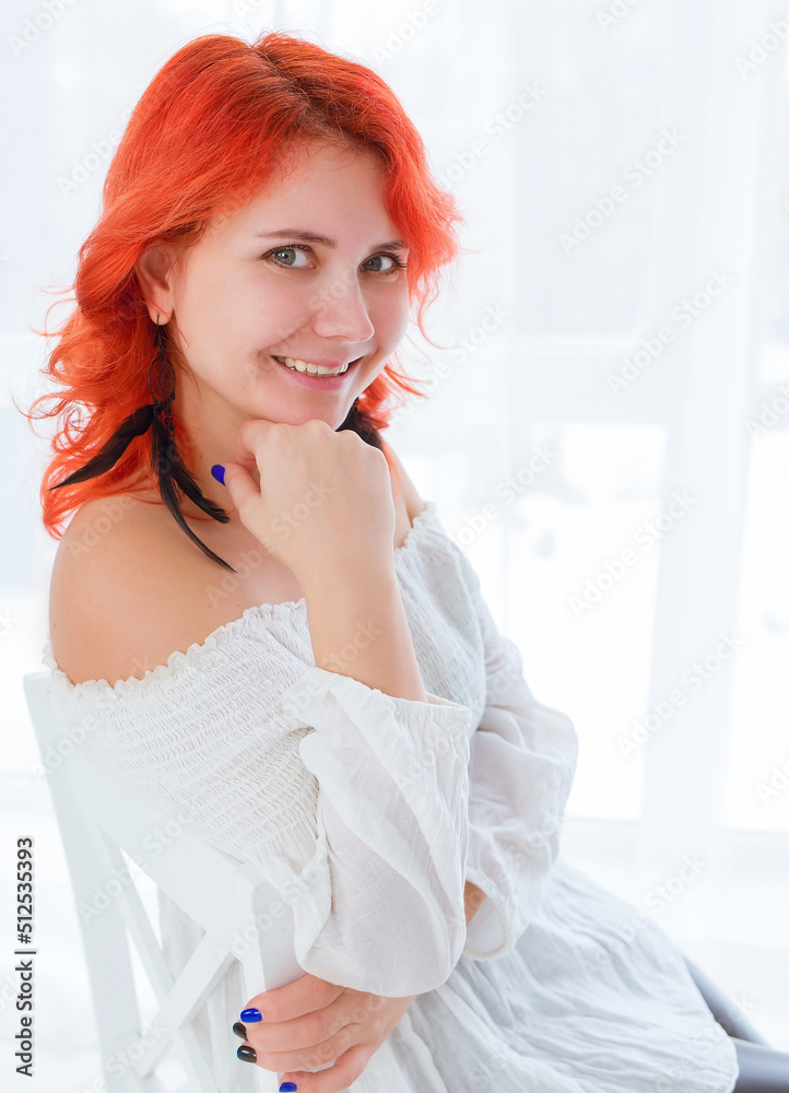 Portrait of a young Caucasian girl with a smile, with red hair in a white blouse sitting indoors. White background. Studio photography. Fashion and beauty Portrait of a young Caucasian girl with a smile, with red hair in a white blouse sitting indoors. White background. Studio photography. Fashion and beauty