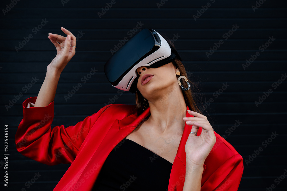 Elegant woman in a red suit using virtual reality goggles on a black background Elegant woman in a red suit using virtual reality goggles on a black background