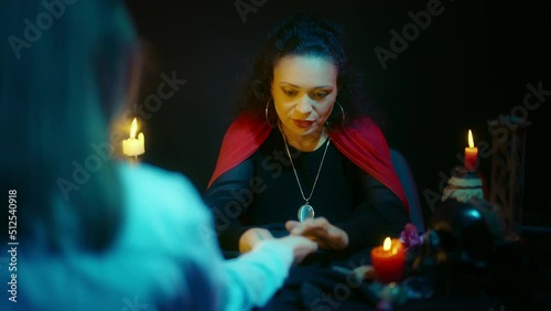 Female fortune-teller looking at client's palm and interpreting lines, palmistry photo