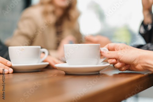 A cup of filter coffee on a table in a coffee shop, a noisy group of friends