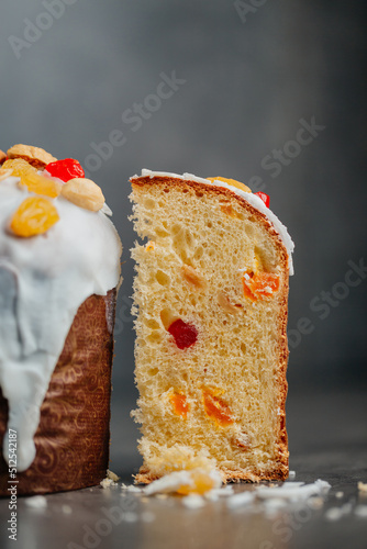 Easter cake, panettone in packaging for sale. Traditional Easter cake cut with raisins, Easter is ready for the holiday on a dark background with slices of dry orange and macaroon, boiled chicken eggs