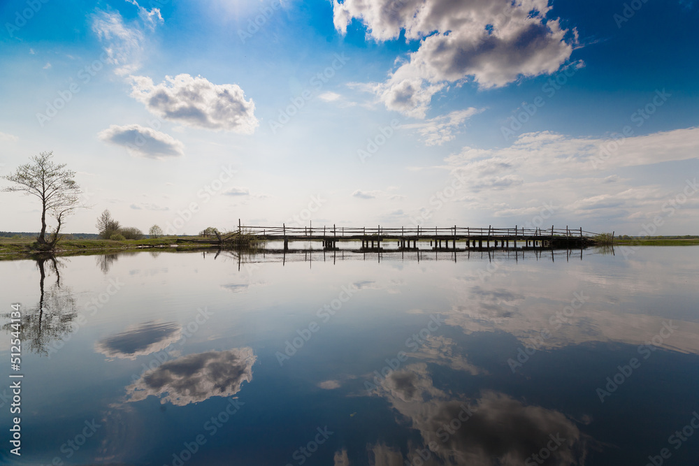 sky and wooden foot bridge reflected in the water