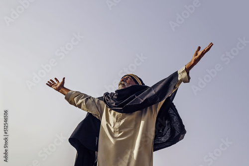 The old Arab spread his arms in supplication to the sky.