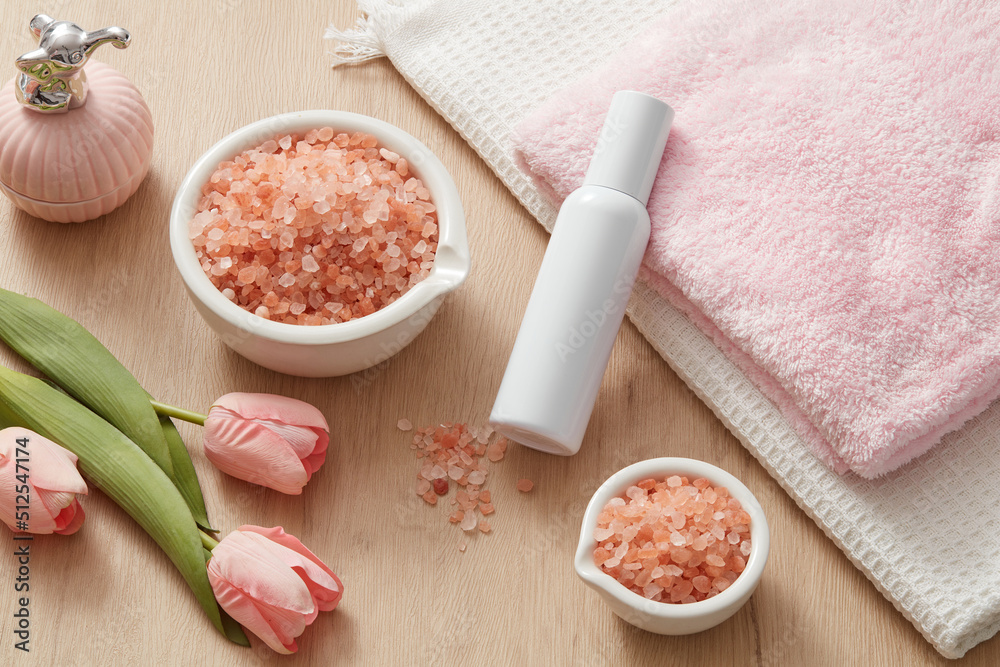 Front view of himalaya salt decorated with tray towel and flower cosmetic jar in table background Front view of himalaya salt decorated with tray towel and flower cosmetic jar in table background