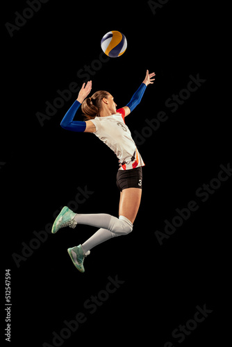 Dynamic portrait of professional volleyball player in sports uniform playing volleyball isolated on dark background. Sport, healthy lifestyle, team, action, motion concept