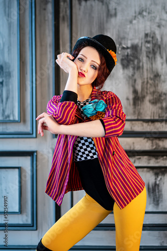 A beautiful animator or cabaret girl dancing in a costume of a ringmaster (entertainer) of an old circus: a red striped tailcoat, a bowler hat, a large buttonhole on her chest. Vintage steampunk style