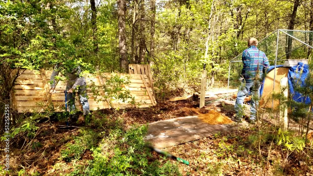 Men prepare site for chicken house construction next to wooded area. Men prepare site for chicken house construction next to wooded area.