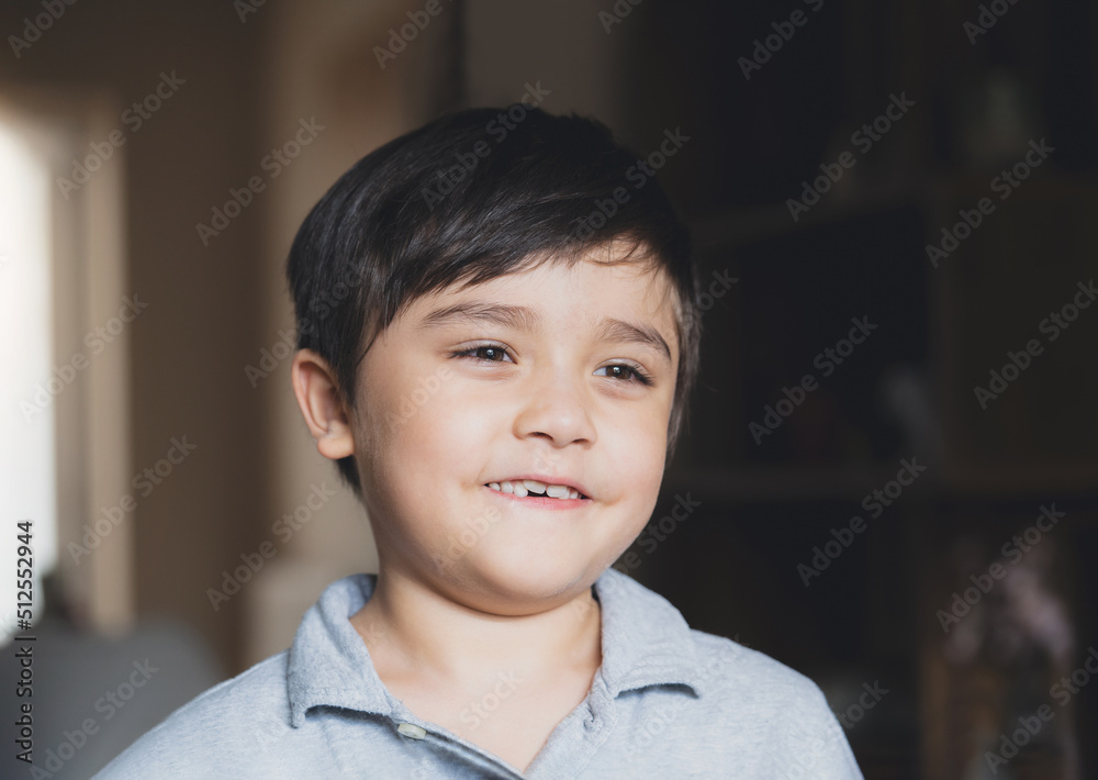 Cinematic Portrait Kid looking deep in thought, Dramatic happy Young boy looking out with smiling face. A child playing alone in living room in evening. Cinematic Portrait Kid looking deep in thought, Dramatic happy Young boy looking out with smiling face. A child playing alone in living room in evening.